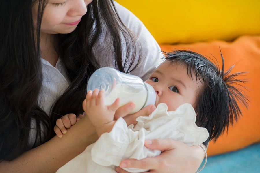 Woman feeding baby infant formula